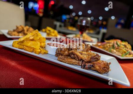 Crispy fried chicken wings with golden fries and spicy dipping sauce on a white plate for culinary promotions. Stock Photo
