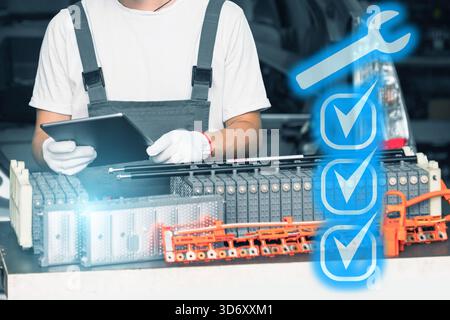 Serviceman repairs electric battery pack of hybrid car using digital tablet Stock Photo