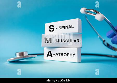 SMA, spinal muscular atrophy. Health concept. Text on white blocks. Blue background, stethoscope. Incurable diseases. Copy space. Close up Stock Photo