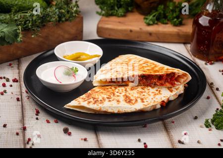 Grilled chicken quesadilla on black plate serving Stock Photo