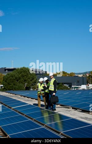 Engineers team inspecting rooftop solar panels on building Stock Photo