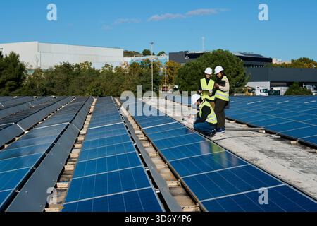 Engineers inspecting solar panels on a factory rooftop Stock Photo