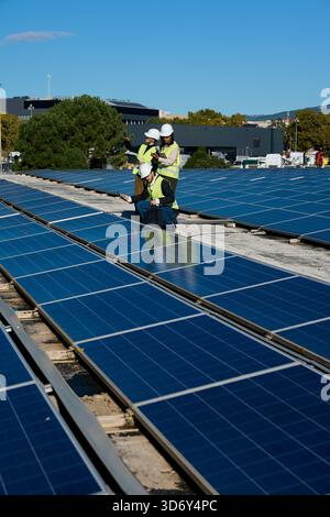 Engineers inspecting rooftop solar panel installation for renewable energy Stock Photo