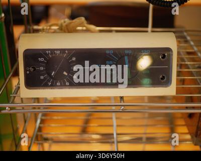 A compact vintage control module with dials and knobs placed on a metal shelf. The device represents retro industrial engineering Stock Photo
