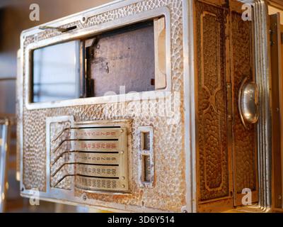 A vintage metal mailbox with an old number plate and mechanical lock is shown in close detail. The aged texture and classic design highlight antique Stock Photo