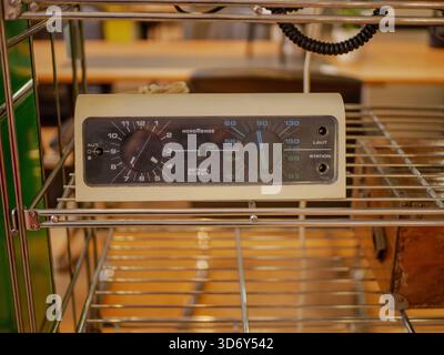 A compact vintage control module with dials and knobs placed on a metal shelf. The device represents retro industrial engineering Stock Photo