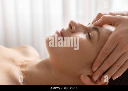 Closeup side view of young woman receiving gentle face massage at spa Stock Photo