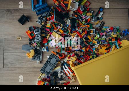 A whole pile of multi-colored Lego bricks spilled out of a yellow box. Photo above. Stock Photo