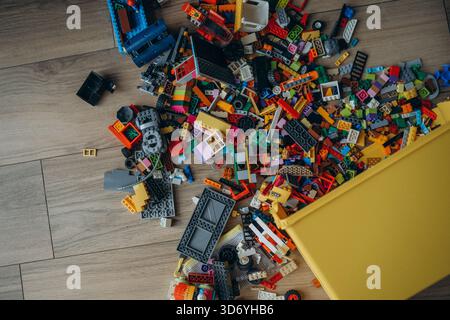 A whole pile of multi-colored Lego bricks spilled out of a yellow box. Photo above. Stock Photo