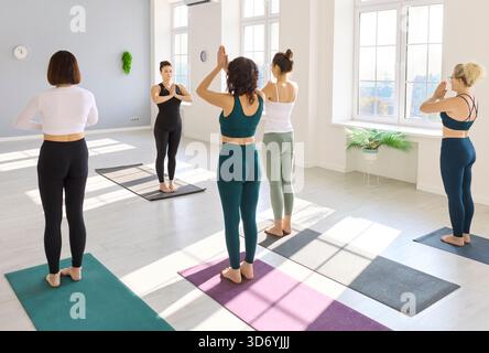 Yoga instructor guiding group of women in sunlit studio during mindful practice Stock Photo