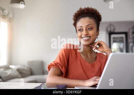 Positive Black freelancer woman enjoying remote work at laptop Stock Photo