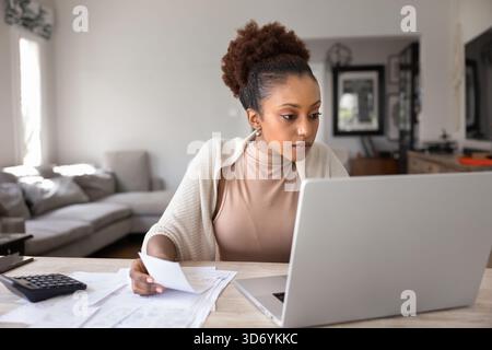 Young African woman calculating domestic budget, analyzing expenses Stock Photo
