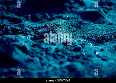 The image is of a blue sand with a blue sky in the background. The sand is wet and the sky is clear Stock Photo