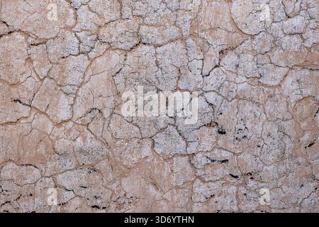 Cracked concrete old wall covered with beige cement surface as background. Textured background old cracked wall, close up. Old wall with cracks textur Stock Photo