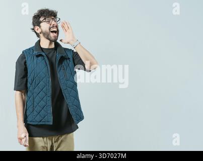 Young man in glasses shouting a promotion isolated. Handsome guy shouting an announcement Stock Photo