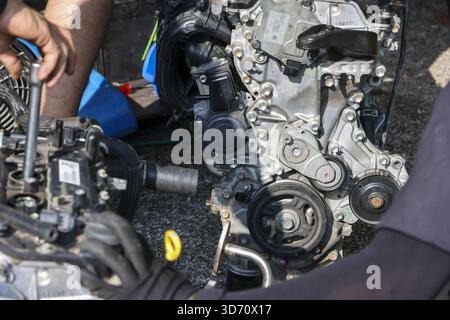 Mechanic hand with tool repairing complex car engine. professional worker at an auto service garage performs maintenance on vehicle motor with deep co Stock Photo