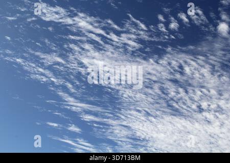 White wispy cirrus clouds scattered across a blue sky Stock Photo