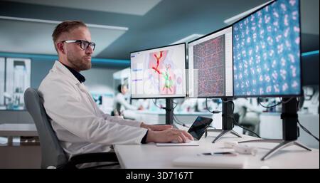 Young Scientist Analyzes Data On Multiple Screens In Busy Laboratory. Architect Designs Hospital Structure On Computer Stock Photo