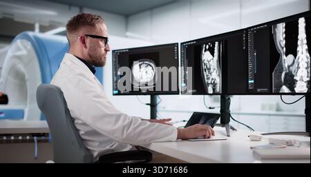 Young Male Surgeon Analyzing Lumbar MRI Scan On Desktop Computer. Stock Photo
