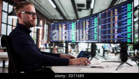 Male Billing Analyst Managing Medical Coding Spreadsheets On Computer Monitor Stock Photo