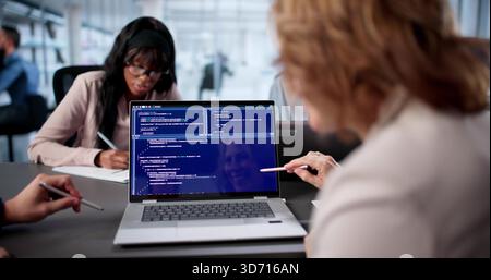 Diverse Team Of Engineers Collaboratively Code Software In Busy Office. Stock Photo