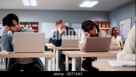 College Students In Classroom Studying With Laptops Look Visibly Bored. Possible Professions: Teacher, Professor Stock Photo