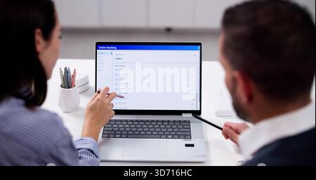Young Couple Checking Savings Account Balance Online On Computer At Home. Financial Analyst Studying Data Reports Stock Photo