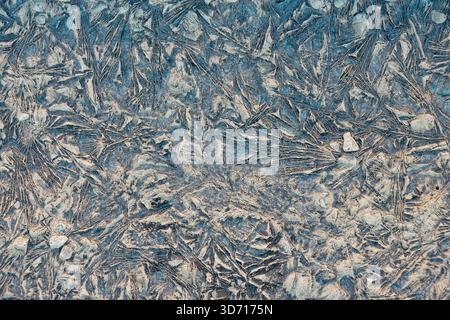 Natural abstract icy patterns on rough surface of frozen ground in winter Stock Photo