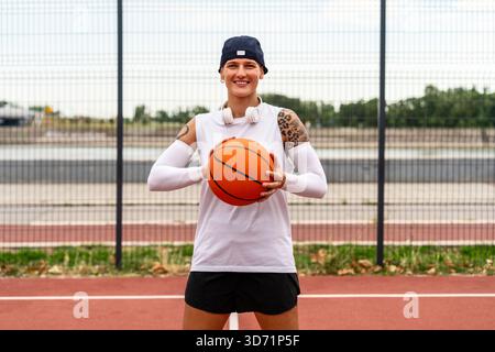 Portrait of young  female street basketball athlete holding ball and smiling. Stock Photo
