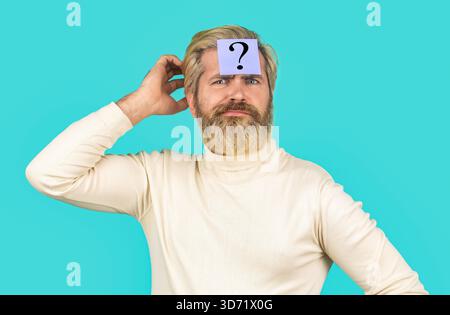 Thinking man with question mark on blue background. Man with question mark on forehead. Paper notes with question marks. Beard man question mark in Stock Photo