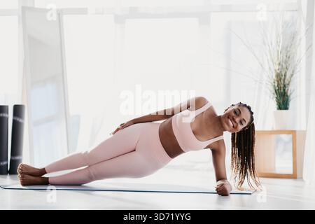 Young Black Woman Practicing Side Plank Yoga at Home for Physical Strength and Flexibility Stock Photo