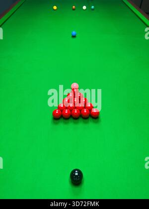 A close-up, high-angle view of several red snooker balls and one pink ball scattered on the bright green felt of a billiards table. Stock Photo