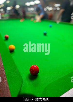 Pekan, Pahang, Malaysia - Nov 23, 2025 : An interior shot of a billiards hall, focusing on a bright green snooker table with several colored Stock Photo
