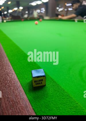 Pekan, Pahang, Malaysia - Nov 23, 2025 : A close-up shot of a small, blue block of billiard chalk resting on the green felt rail of a snooker Stock Photo