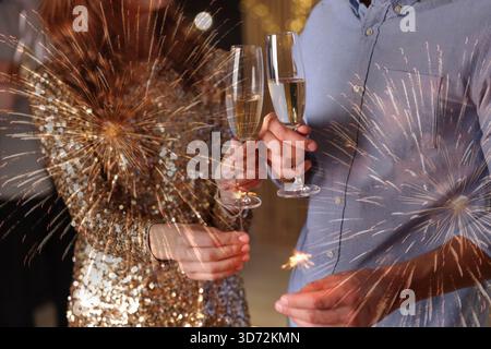 Friends with glasses of sparkling wine and sparklers celebrating New Year, closeup Stock Photo