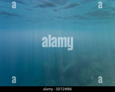 Abstract underwater background with sun rays piercing through deep blue water off the coast of Nice, France. Stock Photo