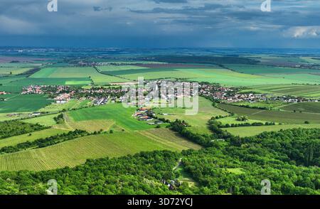 Dark rain cloud with storm over a green field and village Stock Photo