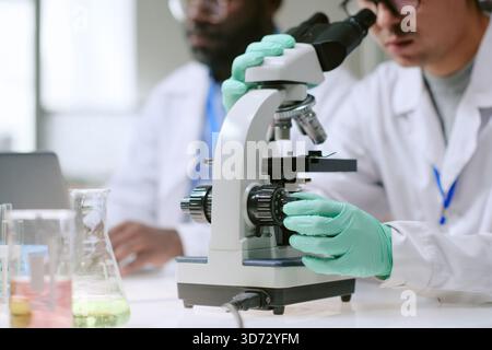 Man and Black Man Using Microscope in Medical Laboratory Stock Photo