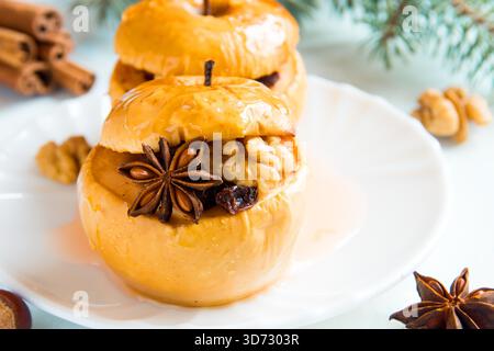 Christmas baked apples stuffed with dried fruit, nuts, cinnamon, anise and honey on white plate close up Stock Photo