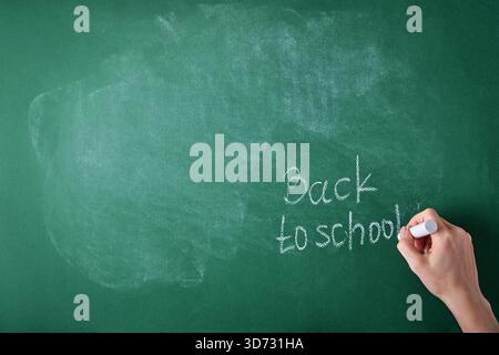 Female teachers hand writing on school board back to school white chalk. Concept back to school. Mock up for design. Copy space. Education Concept. Stock Photo