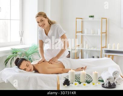 Woman masseur doing relaxing massage for client for body relaxing, posing in cosmetology spa centre Stock Photo