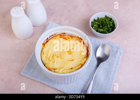 Shepherd's pie in a portioned white baking dish. Homemade traditional casserole (gratin) with minced meat and mashed potatoes. Selective focus, close- Stock Photo