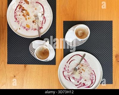 Two coffee cups with empty dessert plates on wooden table, showing remnants of Thanksgiving pumpkin strudel. Concept of shared autumn moment over Stock Photo