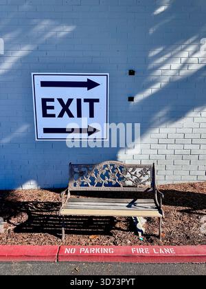 Exit sign on brick wall above decorative bench Stock Photo
