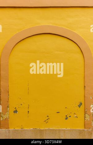 Warm Yellow Archway On Aged Pink-Trim Wall With Weathered Texture And Soft Sunlight Stock Photo