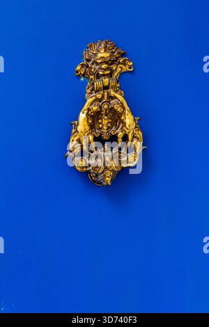 Ornate Brass Lion-Head Door Knocker Mounted On Bright Blue Door for Classic Gothic Home Charm Stock Photo