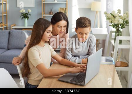 Mother, her son and daughter watching training video lesson, work on laptop computer Stock Photo