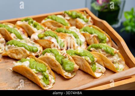 A tray filled with appetizing chicken tacos, topped with creamy guacamole. this vibrant scene captures a flavorful and inviting mexican dish, perfect Stock Photo