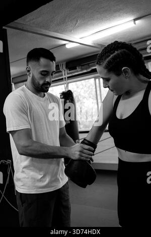 Caucasian man assisting woman with boxing gloves during training Stock Photo