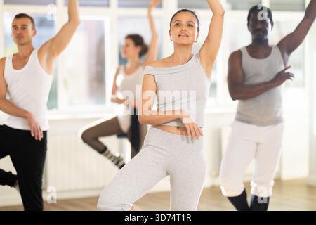 Young Asian woman practicing basic ballet movements at group class Stock Photo